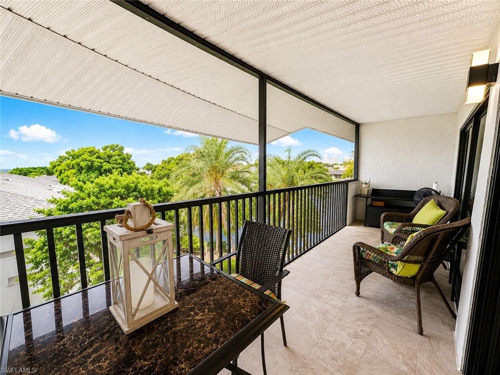 600 Neapolitan Way, Unit 449 Naples, FL 34103 - Photo 20 of 44 Expansive outdoor balcony featuring a neutral tile floor, black metal railing, and a textured white overhead covering