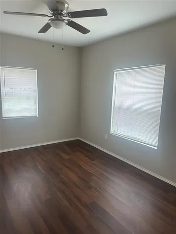 an empty room with wooden floor closet and windows