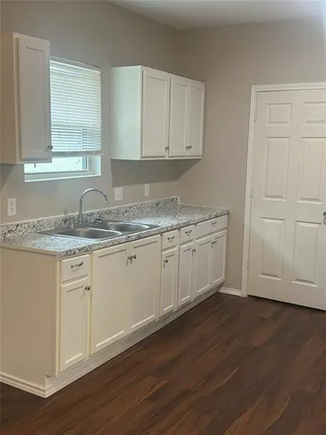 a kitchen with granite countertop white cabinets and a hard wood floors