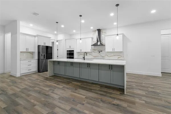 a large kitchen with stainless steel appliances kitchen island a large counter top and a wooden floors