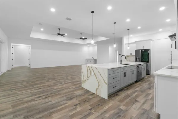 a large white kitchen with kitchen island a sink stainless steel appliances and cabinets