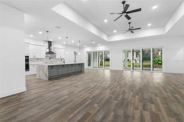 a view of an empty room with wooden floor and a kitchen