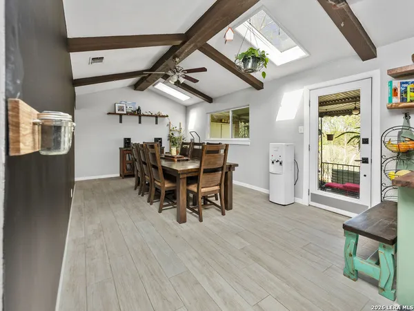 a dining room with wooden floor a chandelier a wooden table and chairs