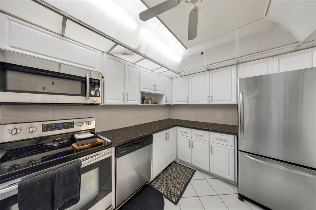 3150 North Course Lane, Unit 203 Pompano Beach, FL 33069 - Photo 3 of 26 a kitchen with stainless steel appliances and white cabinets