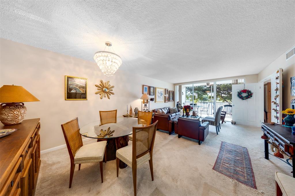 3150 North Course Lane, Unit 203 Pompano Beach, FL 33069 - Photo 6 of 26 a view of a dining room with furniture a rug and wooden floor
