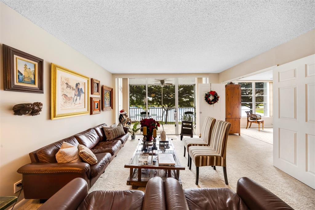 3150 North Course Lane, Unit 203 Pompano Beach, FL 33069 - Photo 8 of 26 a living room with furniture and floor to ceiling windows