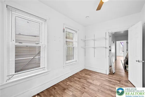 a view of empty room with wooden floor and fan
