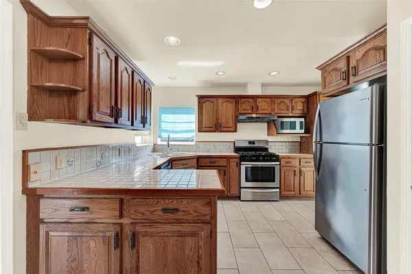 a kitchen with stainless steel appliances granite countertop a refrigerator and a stove top oven