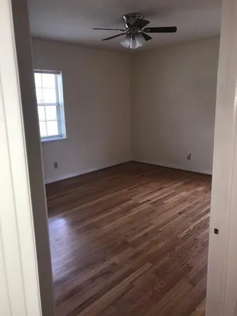 an empty room with wooden floor fan and windows