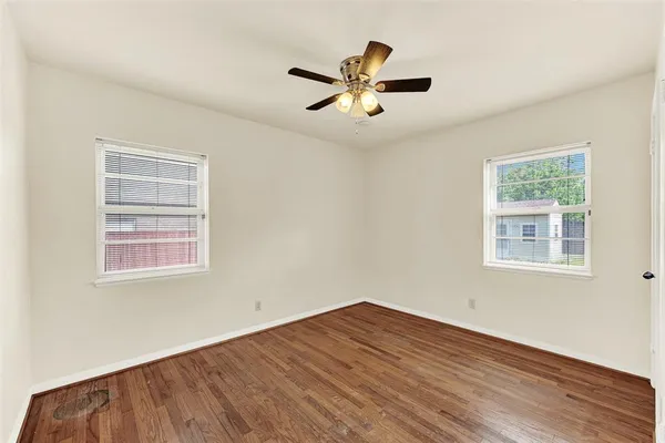 a view of empty room with wooden floor and fan