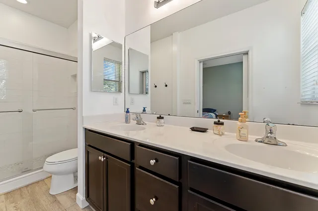 a bathroom with a double vanity sink toilet and mirror
