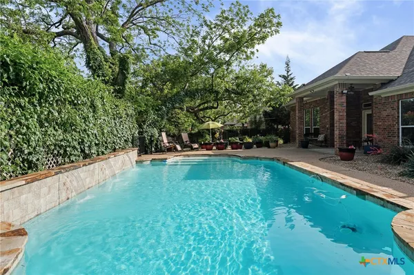 a view of swimming pool with lawn chairs and plants