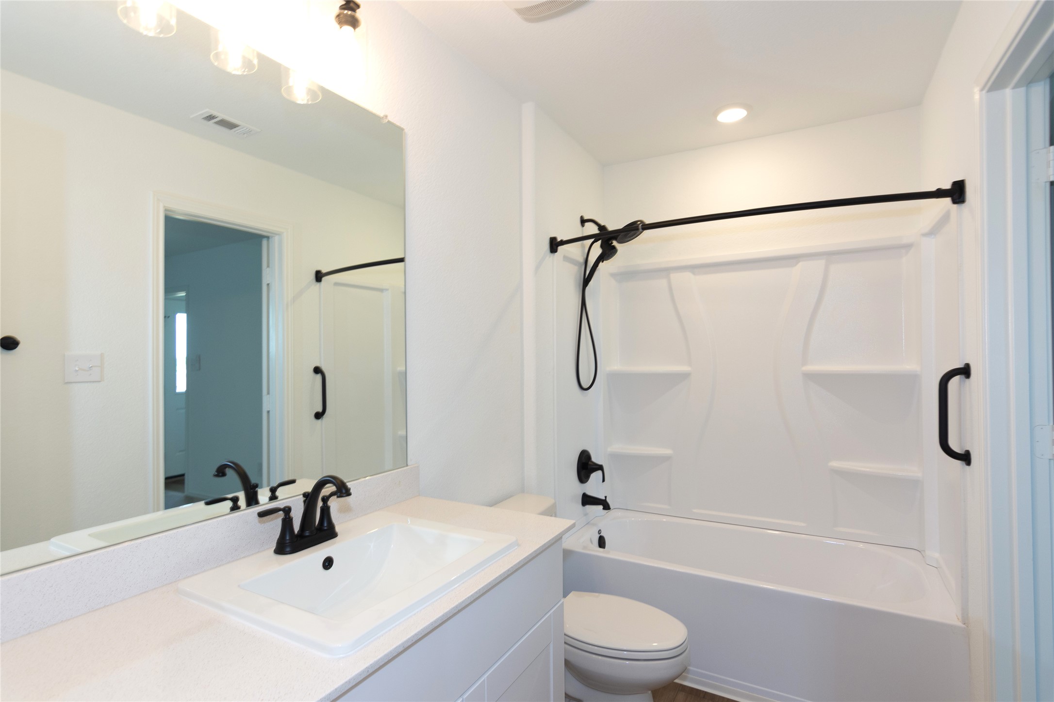 548 Rancho Del Cielo Loop Jarrell, TX 76537 - Photo 17 of 40 Modern primary bathroom featuring a white vanity with an integrated sink and matte black faucet, a large frameless mirror, and a white tub/shower combination with matte black fixtures