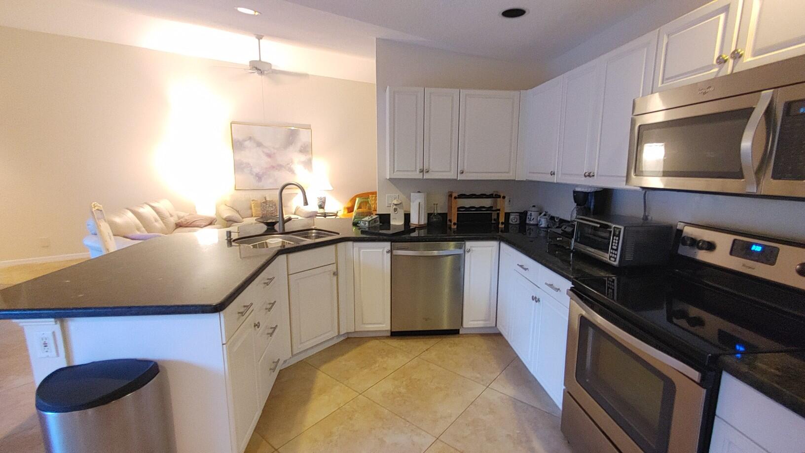 16461 Riverwind Drive Jupiter, FL 33477 - Photo 15 of 45 a kitchen with granite countertop a sink a stove and cabinets