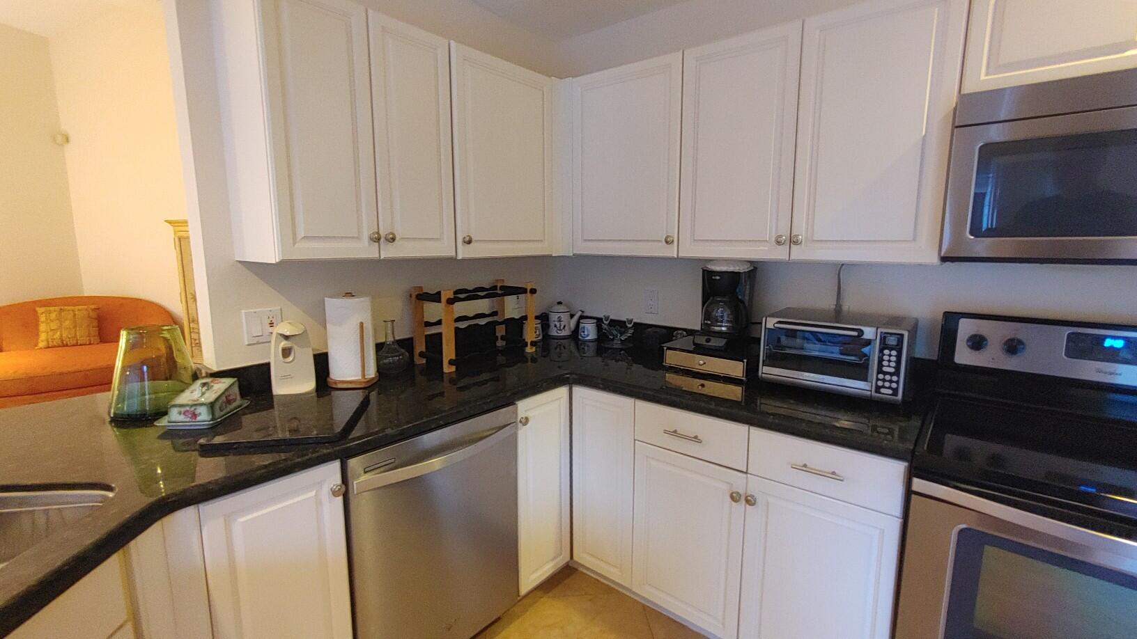 16461 Riverwind Drive Jupiter, FL 33477 - Photo 16 of 45 a kitchen with granite countertop white cabinets and white appliances