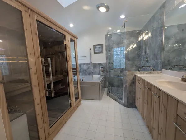 a bathroom with a double vanity sink a toilet a mirror and tub