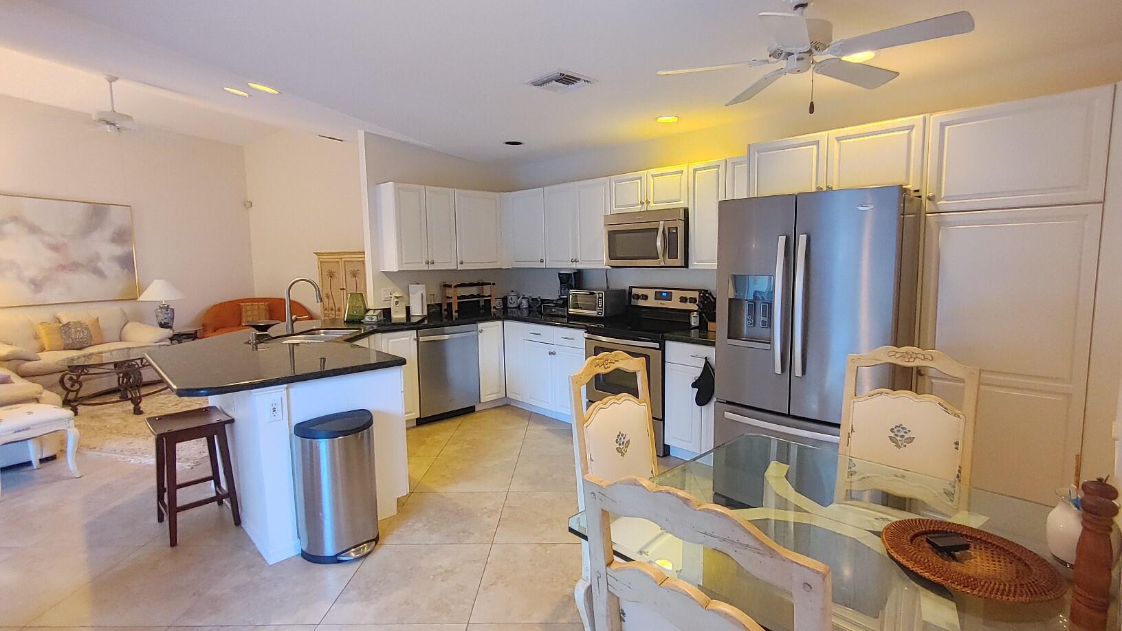 16461 Riverwind Drive Jupiter, FL 33477 - Photo 9 of 45 a kitchen with stainless steel appliances a refrigerator a sink a stove a microwave a center island and furniture