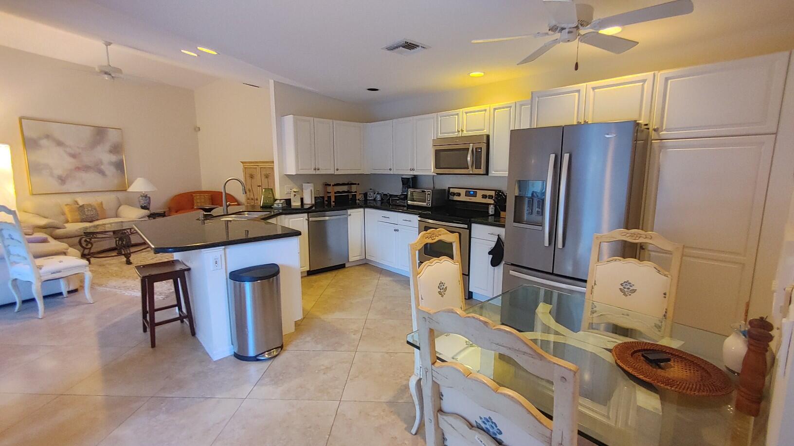 16461 Riverwind Drive Jupiter, FL 33477 - Photo 10 of 45 a kitchen with refrigerator and chairs