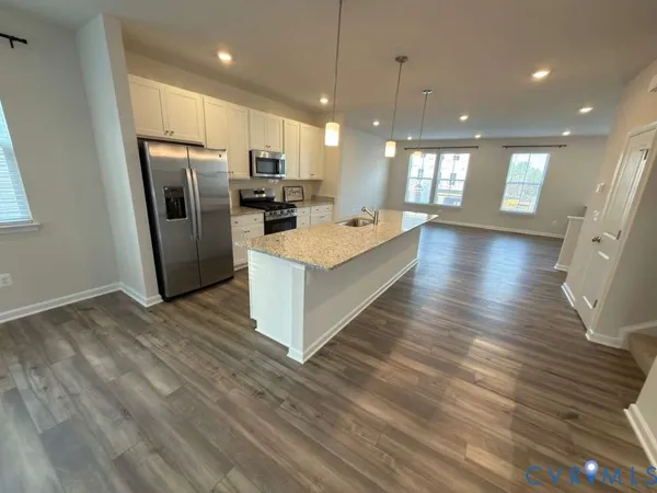 a view of kitchen with kitchen island granite countertop wooden floors and a view of living room