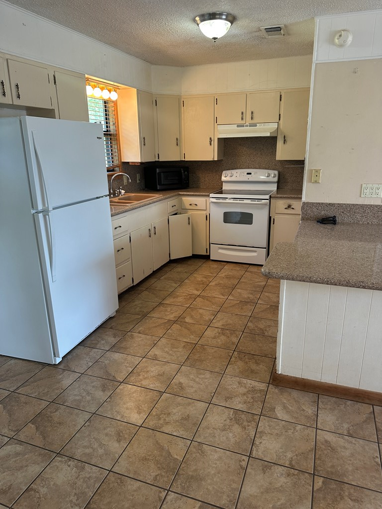 104 South Ave B Mason, TX 76856 - Photo 11 of 26 a kitchen with granite countertop a refrigerator sink stove and cabinets