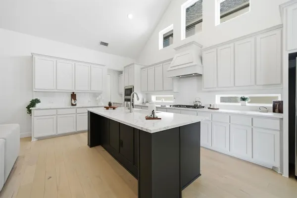 a kitchen with kitchen island granite countertop a sink cabinets and stainless steel appliances