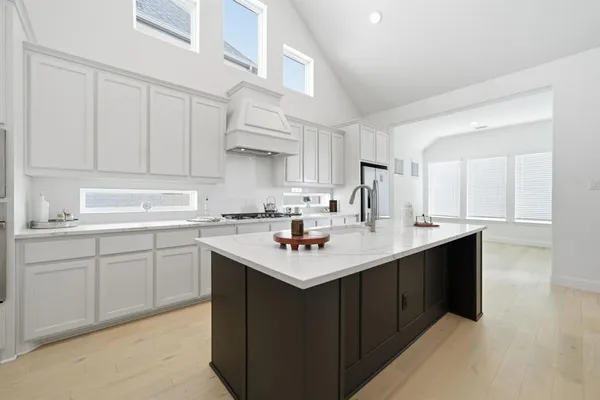 a kitchen with stainless steel appliances granite countertop a sink dishwasher and white cabinets with wooden floor