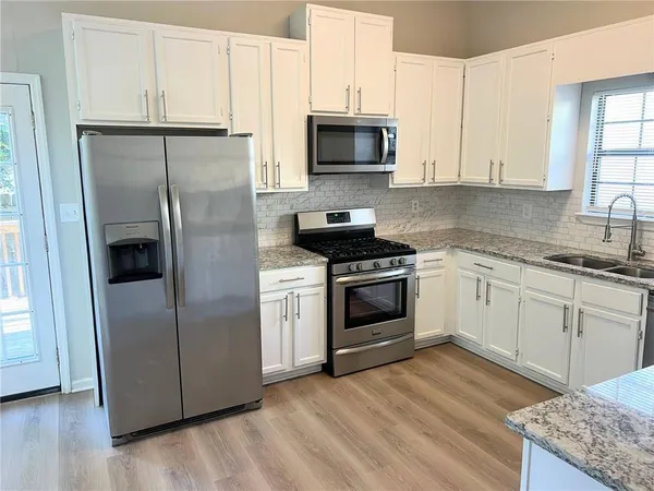 a kitchen with a sink a microwave a refrigerator and cabinets