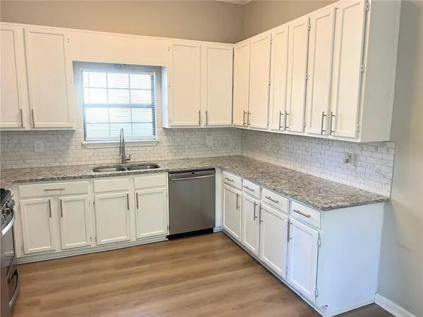 a kitchen with granite countertop white cabinets and white appliances