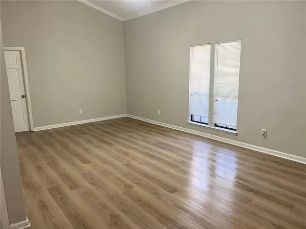 an empty room with wooden floor and windows