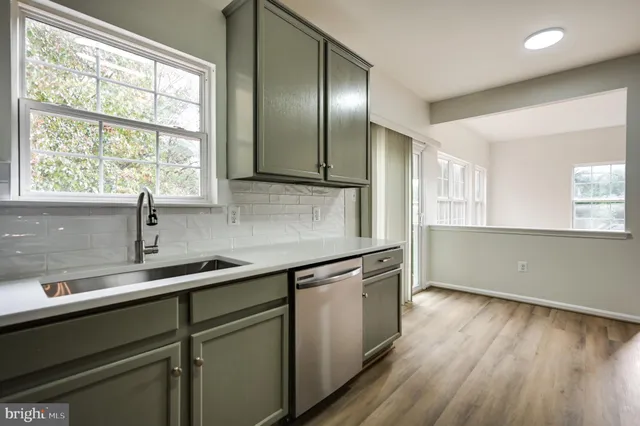 a kitchen with stainless steel appliances granite countertop a sink a window and wooden floor