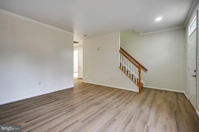 a view of an empty room with wooden floor and stairs