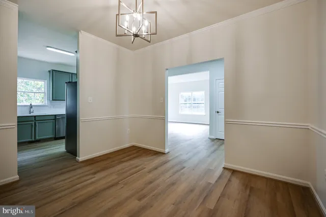 a view of a hallway with wooden floor and a kitchen