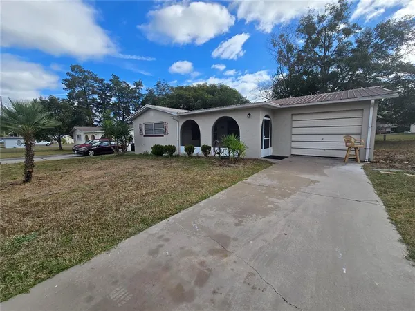 a view of a house with a yard and large tree