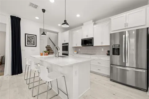 a kitchen with stainless steel appliances kitchen island granite countertop a sink a stove a dining table and chairs