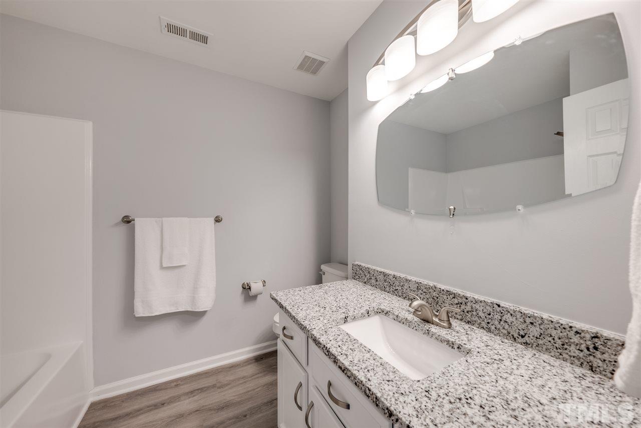 5408 Gunnette Drive Raleigh, NC 27610 - Photo 21 of 23 a bathroom with a granite countertop sink a mirror and vanity