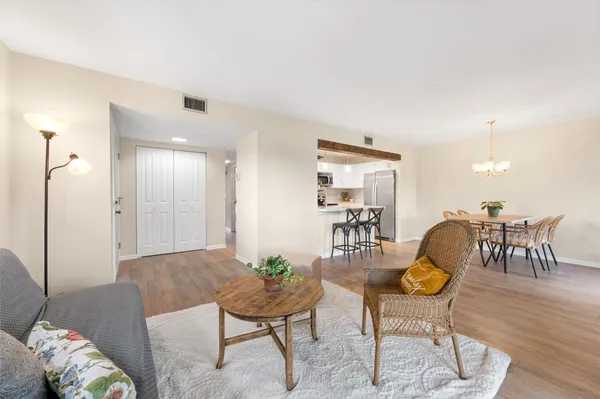a view of a dining room and livingroom with furniture wooden floor a chandelier