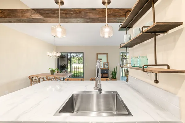 a kitchen with stainless steel appliances granite countertop a stove top oven a refrigerator and a dining table