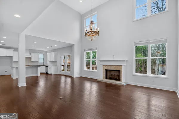 an empty room with wooden floor fireplace and windows