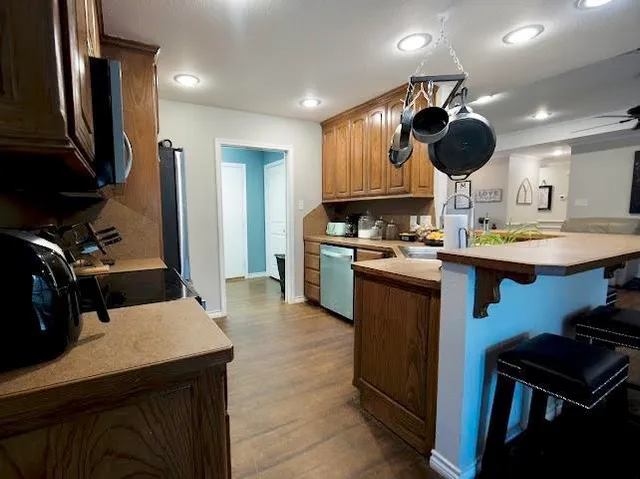 a kitchen with stainless steel appliances granite countertop a sink dishwasher stove and wooden cabinets