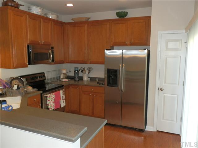 7147 Racine Way Raleigh, NC 27615 - Photo 6 of 12 a kitchen with stainless steel appliances granite countertop a refrigerator a stove and a sink with wooden cabinets