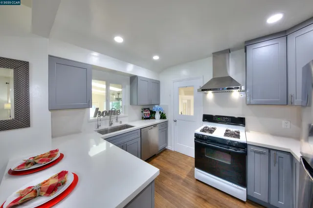 a kitchen with stainless steel appliances granite countertop a sink a stove and a wooden floors