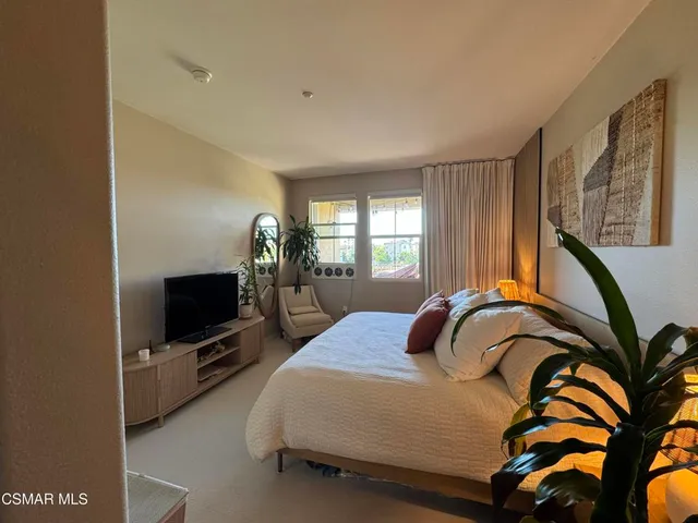 a bedroom with a bed and a potted plant