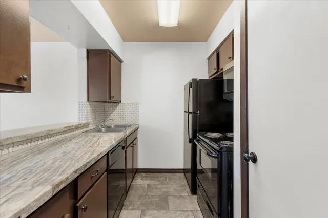 a kitchen with granite countertop a stove microwave and refrigerator