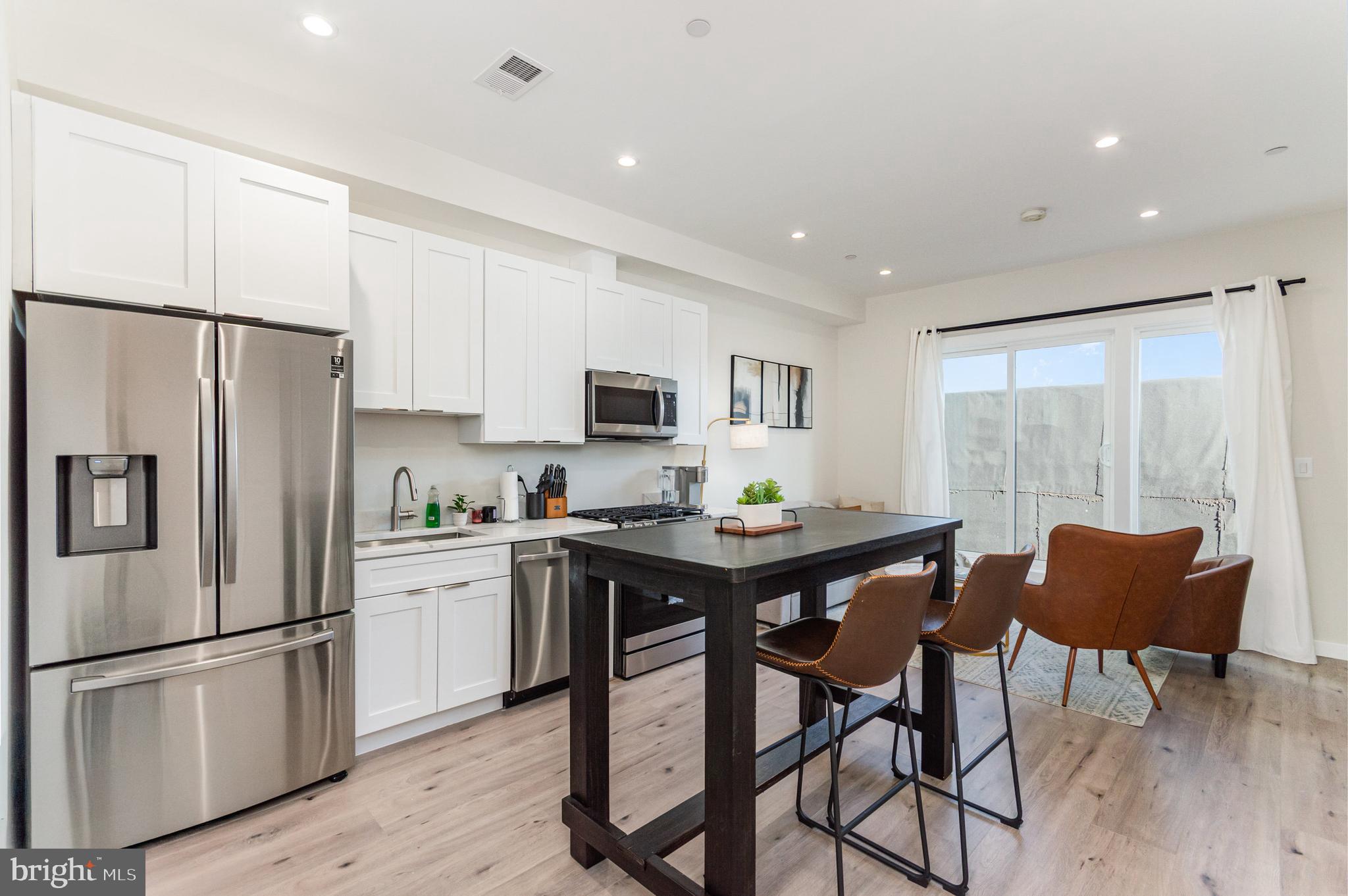 2116 4th Street Northeast, Unit A Washington, DC 20002 - Photo 15 of 17 a kitchen with stainless steel appliances granite countertop a refrigerator a stove a sink a dining table and chairs with wooden floor