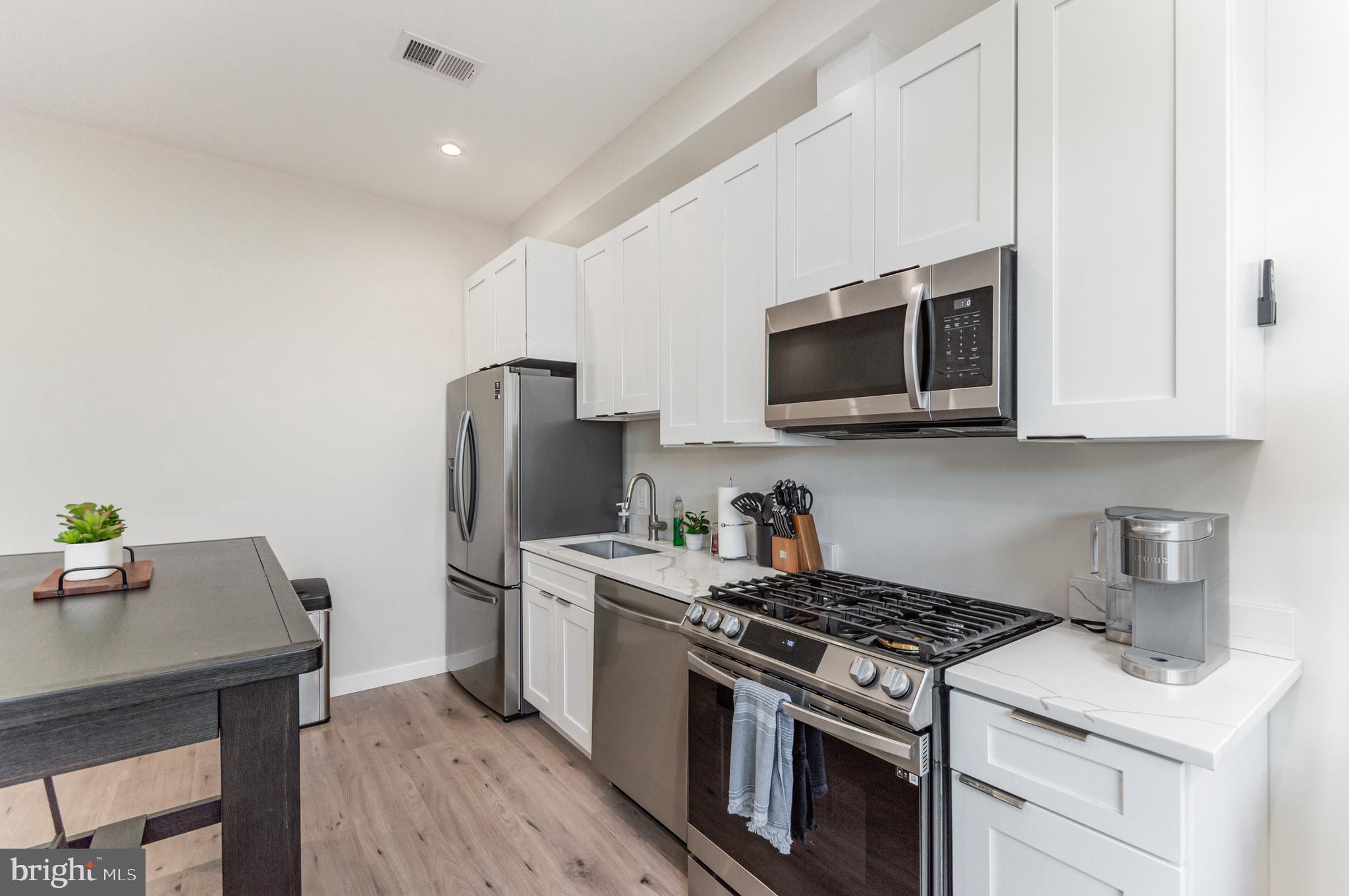 2116 4th Street Northeast, Unit A Washington, DC 20002 - Photo 3 of 17 a kitchen with stainless steel appliances a stove a microwave a sink a refrigerator white cabinets and wooden floor