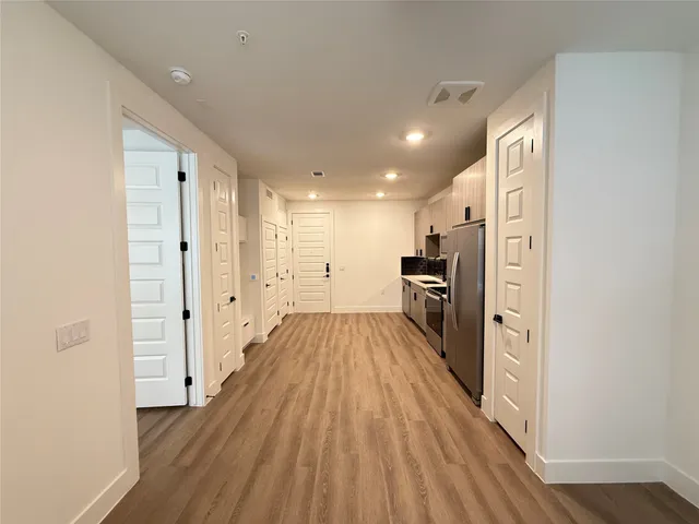 a view of a hallway with wooden floor and a living room