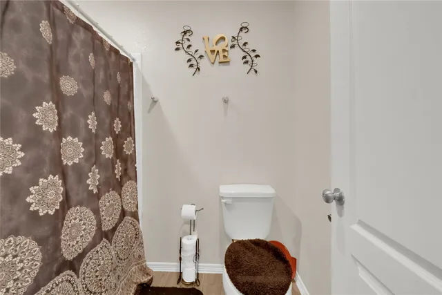 a bathroom with a toilet and a shower curtain