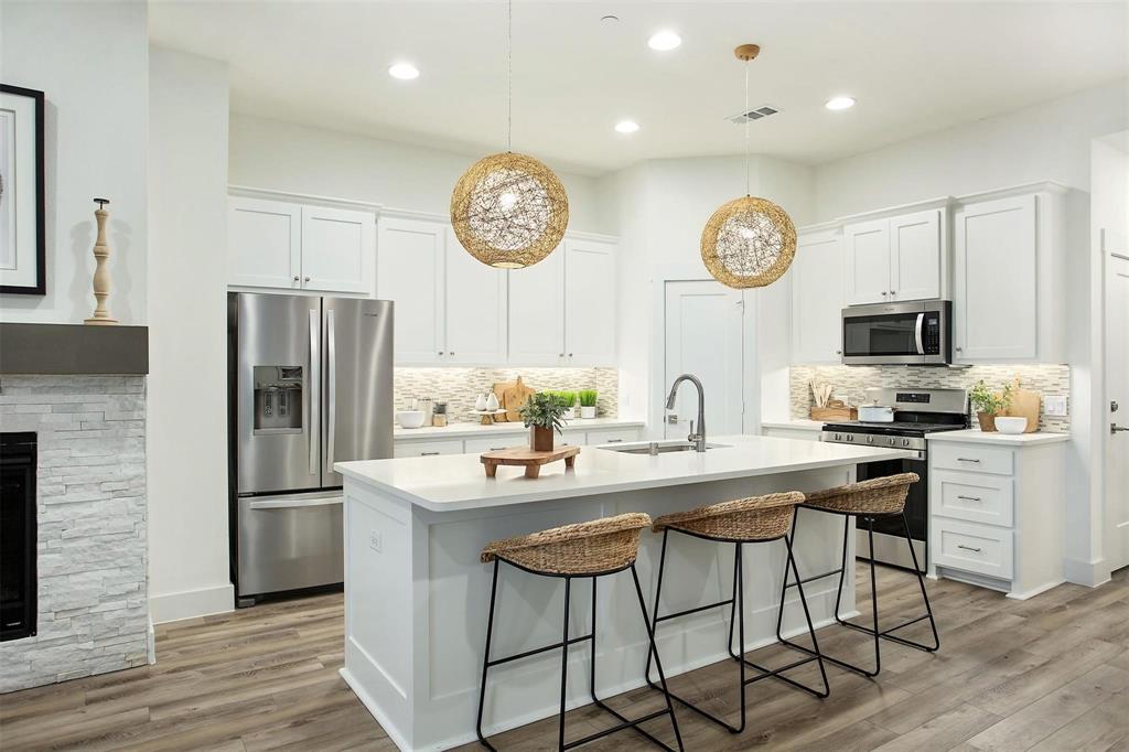 a kitchen with stainless steel appliances a stove a refrigerator a dining table and chairs