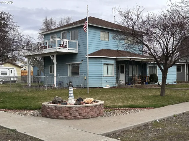 a front view of a house with a garden and trees