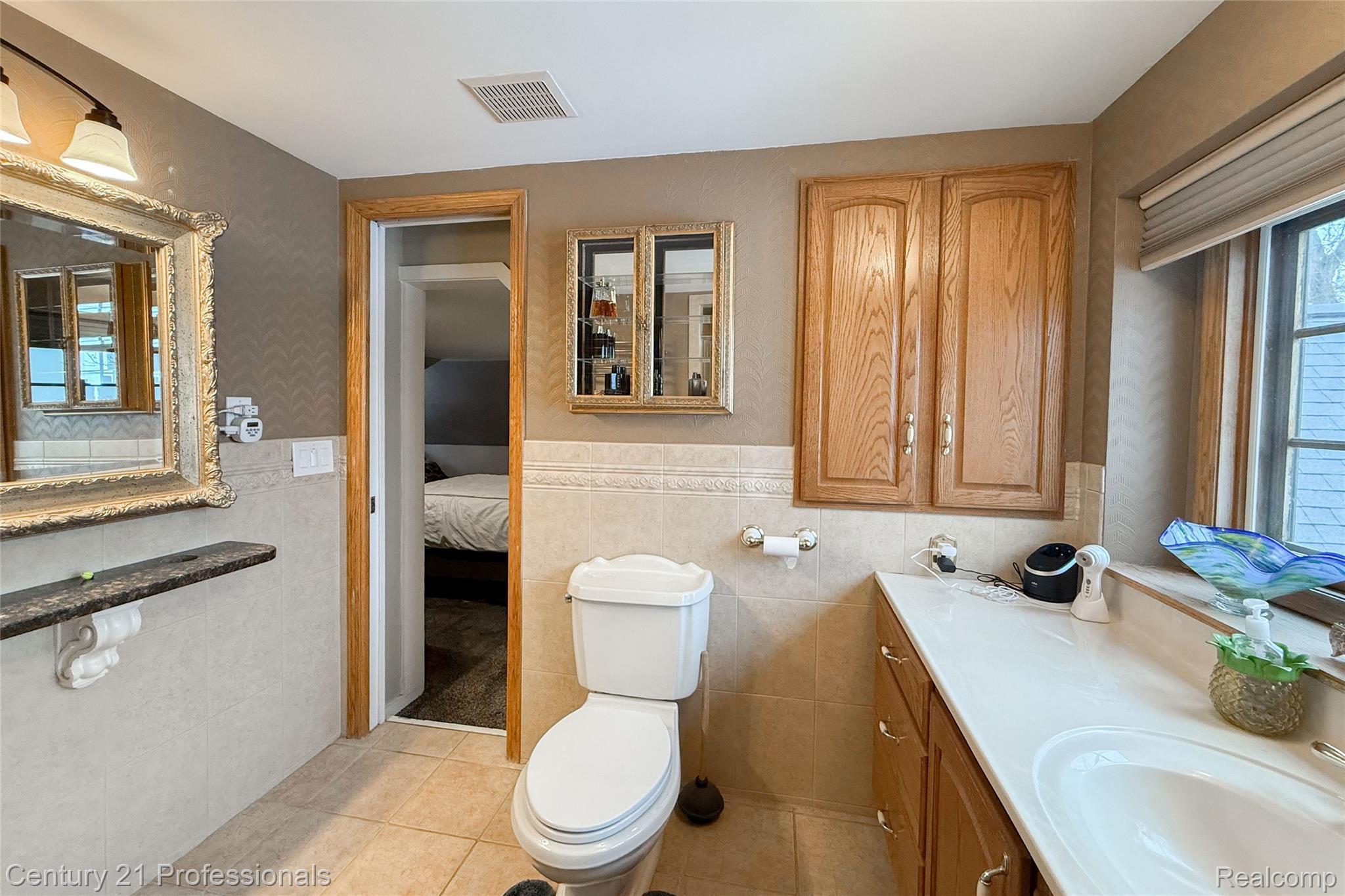 910 West Pine Tree Road West Lake Orion, MI 48362 - Photo 32 of 52 Ensuite bathroom with vanity, light tile patterned flooring, wainscoting, and wallpapered walls